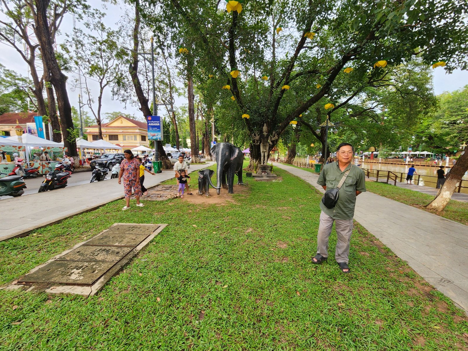 Elephant statues line the riverside walkway with yellow lanterns above