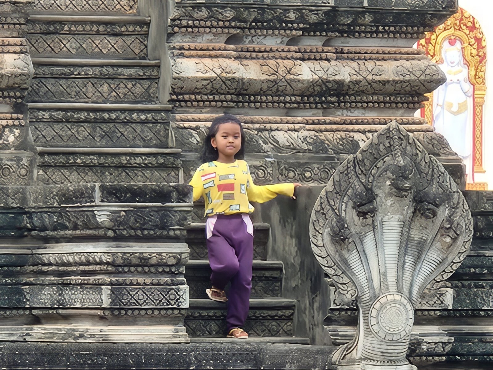 A young Khmer girl climbs the naga serpent stairway