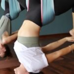 Two women hanging upside down in aerial yoga hammocks during a class at Aum Yoga Center in Siem Reap