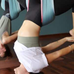 Two women hanging upside down in aerial yoga hammocks during a class at Aum Yoga Center in Siem Reap